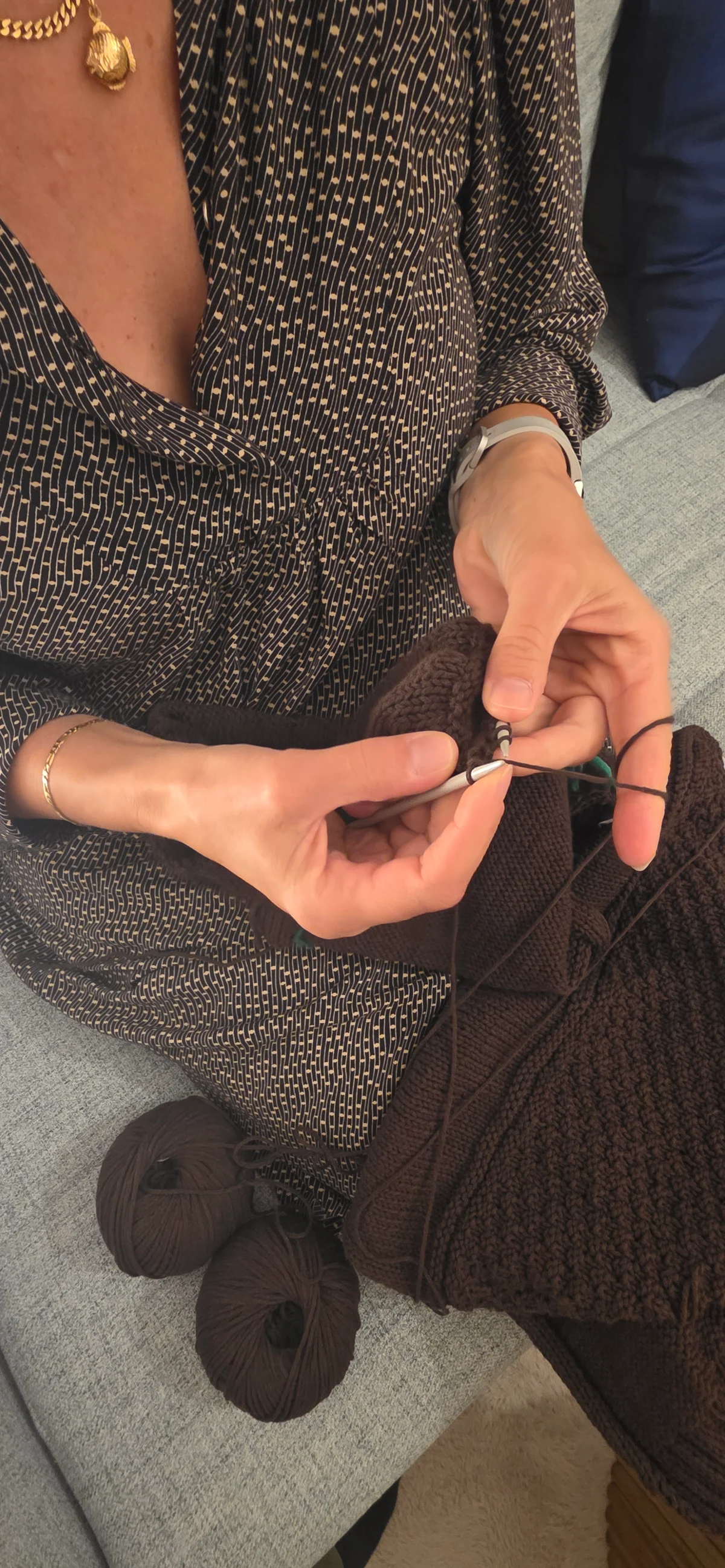 Claudia beim Stricken, mit Nadeln, Strickstück und Garn auf ihrem Schoss